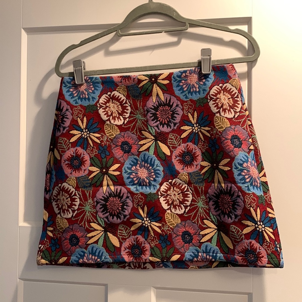 Woven mini skirt with floral pattern. Burgundy base color with colorful flowers.